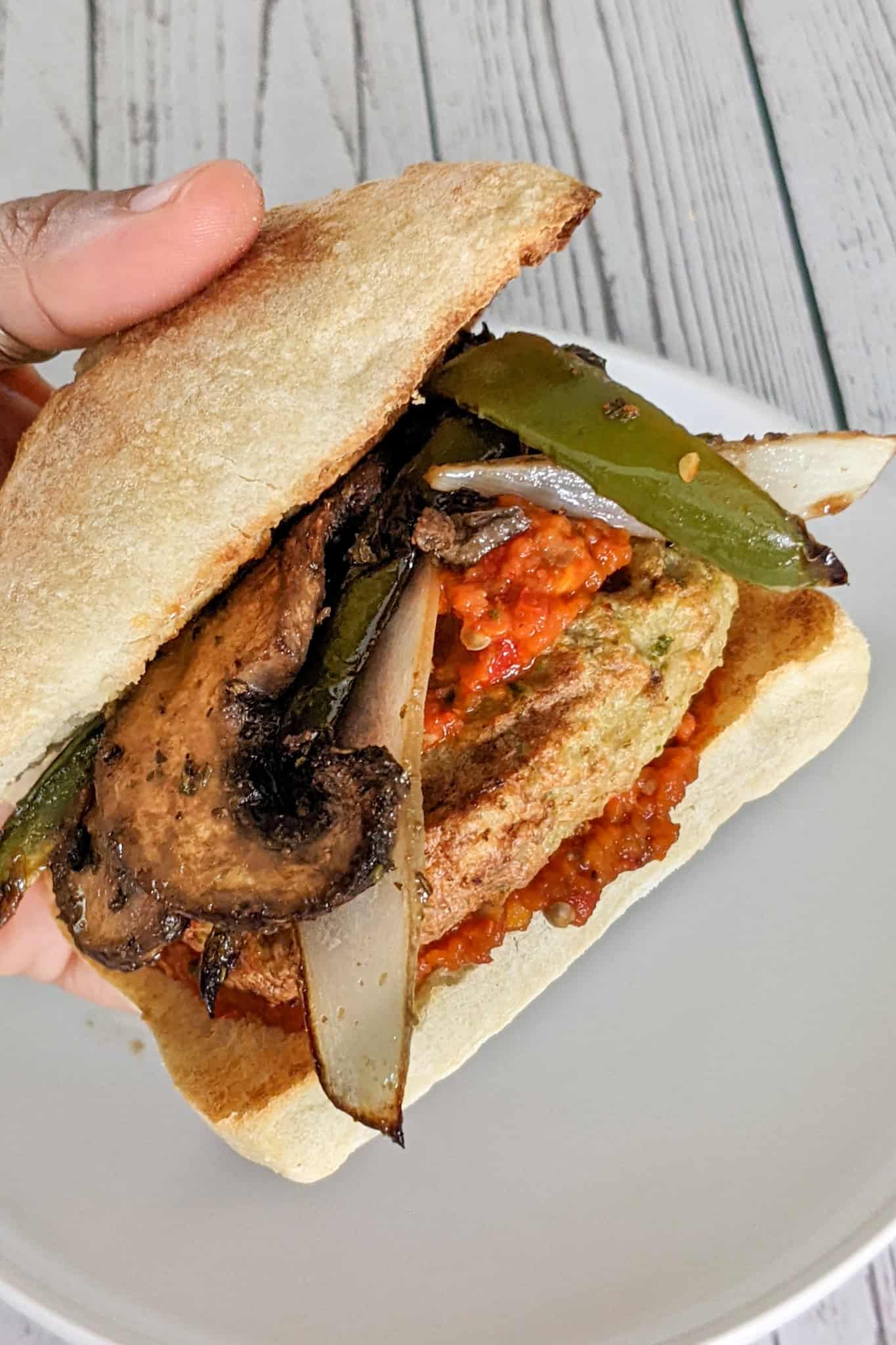 Close-up of a spicy chicken burger with harissa, eggplant, and mushrooms.